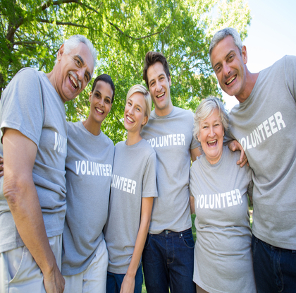A group of volunteers wearing matching t-shirts stands together outdoors